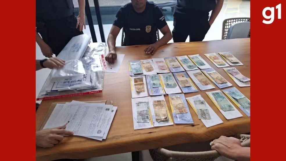 Policiais cumprem mandados durante operação que investiga uma família suspeita de agiotagem em Cuiabá.